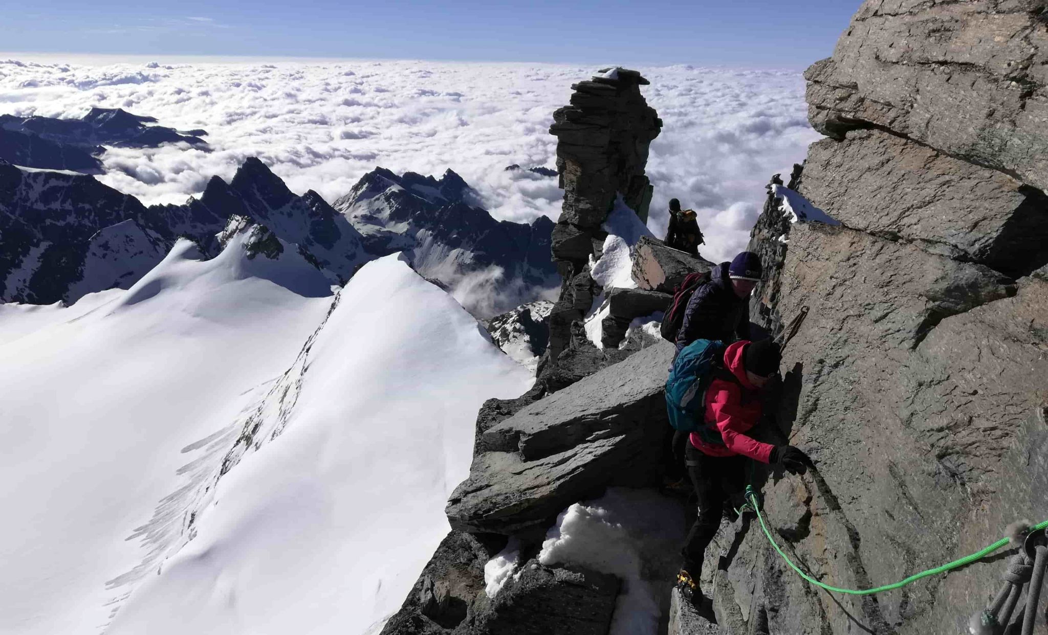 Alpinisti legati in cordata negli ultimi metri per arrivare alla cima del Gran Paradiso, il passaggio esposto è assicurato da una Guida Alpina non visibile nella foto