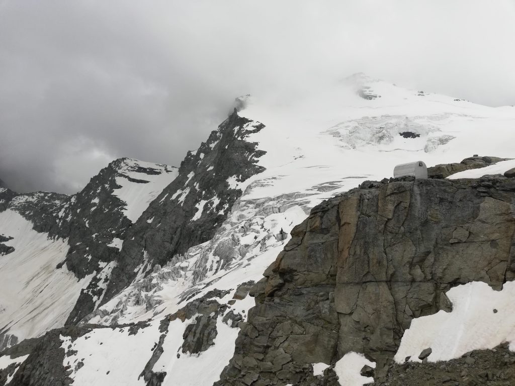 Il bivacco Grappein con sullo sfondo la Testa di Ceresole e il ghiacciaio della Tribolazione