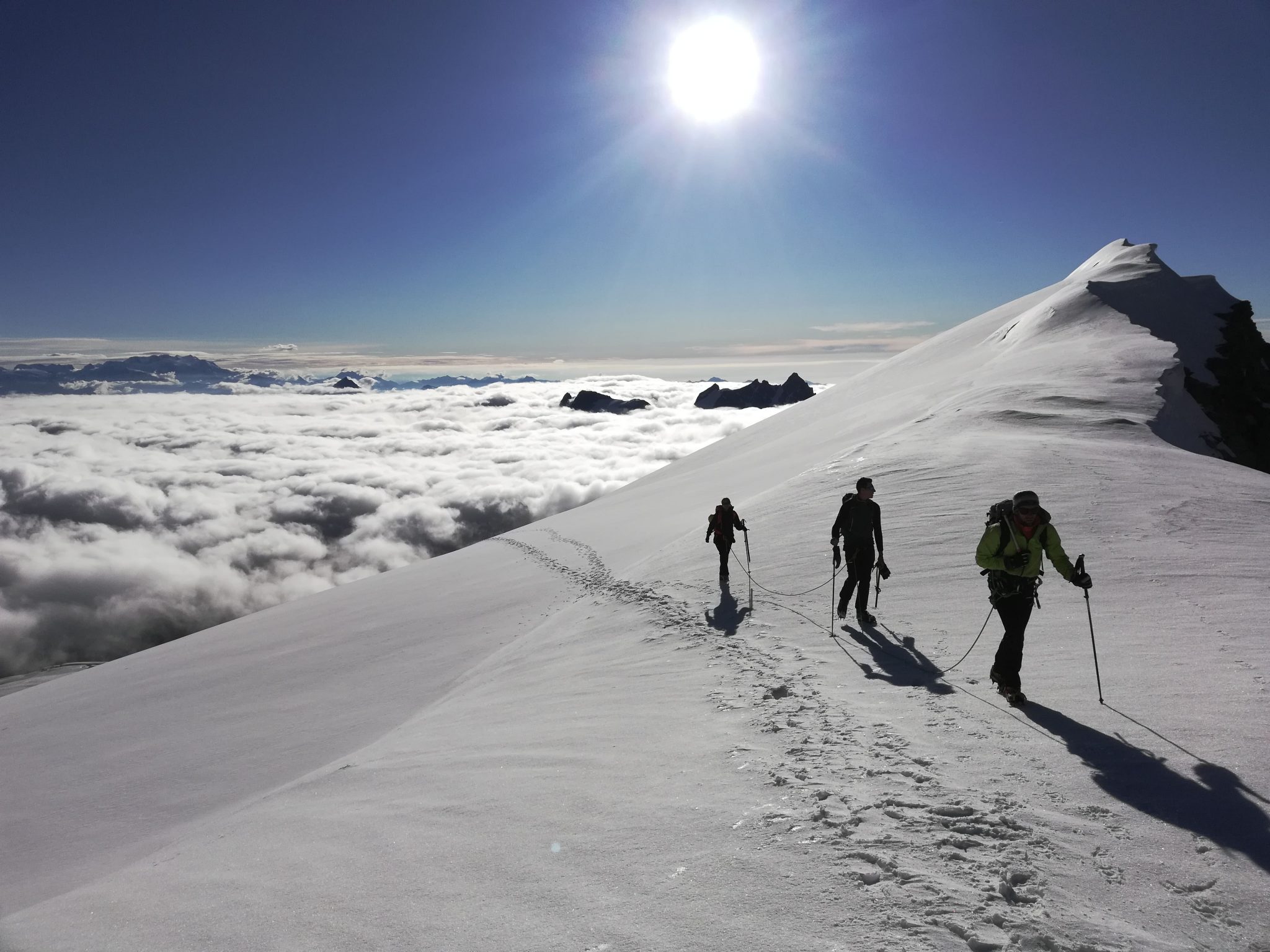 Alpinisti in cordata con guida alpina nei pressi del colle dell'Ape. Sullo sfondo un mare di nuvole