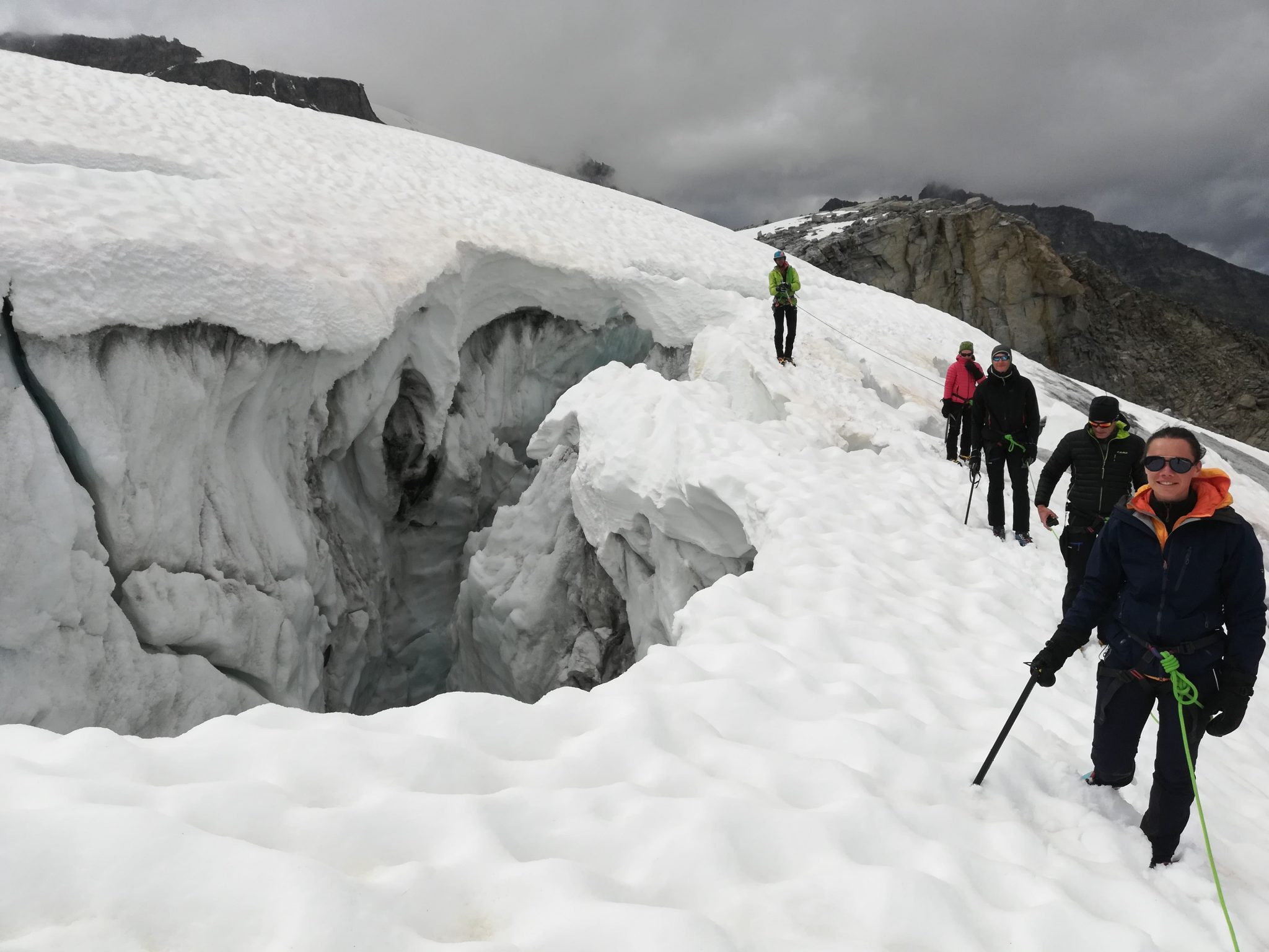 alpinisti legati in cordata con Guida Alpina attraversano crepacci su ghiacciaio