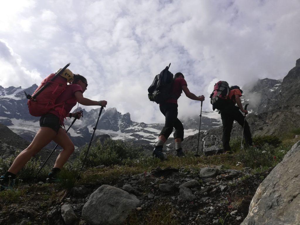 Alpinisti salgono verso il bivacco Pol Grappein assieme alla loro Guida Alpina. Sullo sfondo le vetta della Becca di Gay e della Roccia Viva