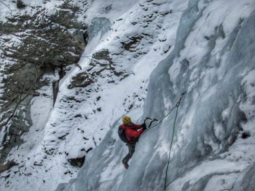 scalatore arrampicata una cascata di ghiaccio utilizzando due piccozze. E' assicurato da una corda di sicurezza