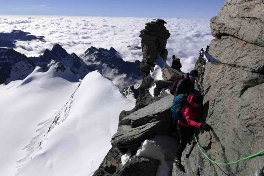 Alpinisti legati in cordata negli ultimi metri per arrivare alla cima del Gran Paradiso, il passaggio esposto è assicurato da una Guida Alpina non visibile nella foto